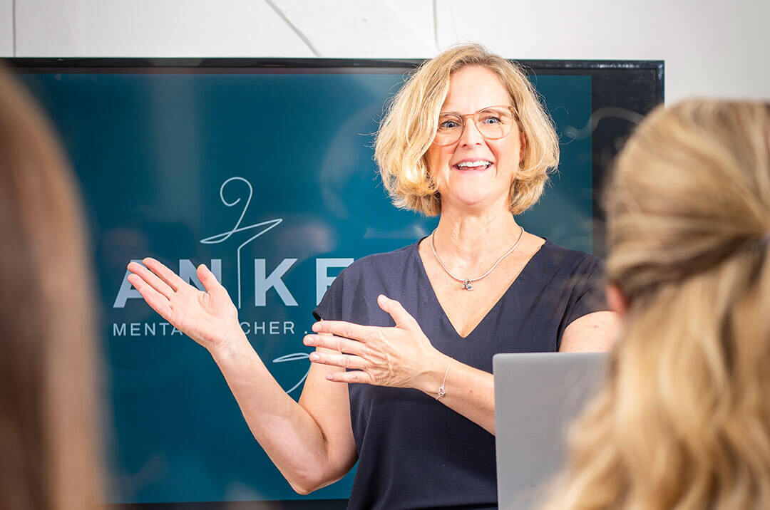 Kerstin Angermeier hält einen Vortrag über mentale Gesundheit am Arbeitsplatz und deutet auf einen Monitor. 